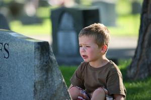 Baby crying in front of a headstone